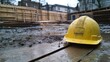 © The 2R Artificiality - Hard hat resting on wooden plank in urban construction site with muddy ground and wooden framing in background