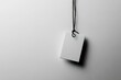 © Graph Squad - Blank white tag hanging from a black string against a light gray background. Perfect for mockup or branding purposes.