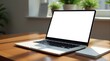 © Александр Бердюгин - Modern laptop with a blank white screen on a wooden desk, accompanied by a small card, next to a plant, creating a minimalistic workspace setting