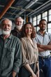 © Natalia - Five professionals pose together in an industrial setting with high ceilings.