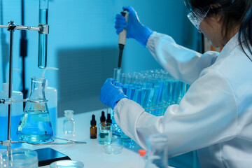 Wall Mural - scientist wearing protective gear using micropipette, analyzing blue liquid in test tubes inside a m