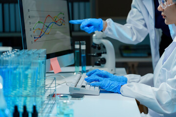 Wall Mural - two scientists wearing lab coats and gloves are analyzing data displayed on a computer screen in a l