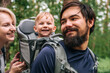 © Julia Suhareva - Happy family on a hike with a child in a travel backpack. laugh, smile, get together and have a good time together