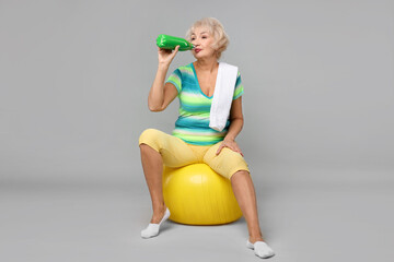 Sticker - Senior woman with fitness ball, water and towel on light grey background