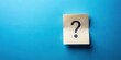 © udomsak - A piece of note paper with a question mark on it, placed on a panoramic blue background with subtle gradient and soft focus effect , note paper question mark panoramic blue background, blank slate