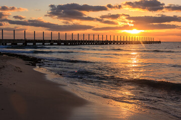 Wall Mural - The sun is setting over the ocean, casting a warm glow over the water