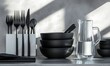 © EFA - A modern table setting featuring black utensils and bowls alongside a glass pitcher.
