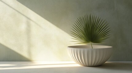 Poster - Single palm leaf in a white bowl on a light green wall with sunlight.
