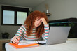© Cavan Images - Tired student having headache while studying online at home