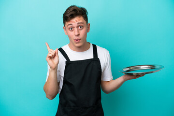 Wall Mural - Young waitress with tray isolated on blue background intending to realizes the solution while lifting a finger up