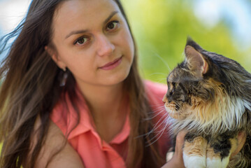 Wall Mural - Portrait of a young beautiful long-haired girl, in light clothes in the summer, in the park with a cat.