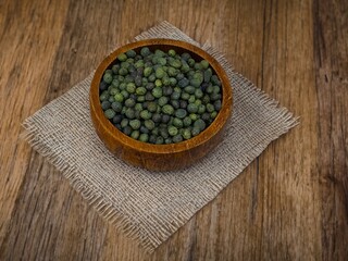 Wall Mural - Dry green pistacia terebinthus or terebinth or turpentine seeds. Menengic seeds in a white plate isolated on black background. Citlembik fruits. Close-up. Menengic, hackberry healthy fruits.
