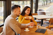 © New Africa - Colleagues with laptop working together at table in cafe