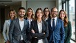 © miss irine - Group of diverse business professionals stand united in contemporary office space. Smiling confident team members look directly at camera. Teamwork, collaboration evident in professional attire.