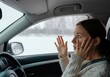 © Sandor - Young woman driving having a car breakdown during winter, looking scared and worried