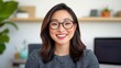 © medalinebow - Young woman smiling with glasses in modern workspace at home