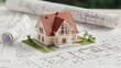 © Cheewynn - A miniature house model sits on architectural blueprints, symbolizing home design and planning in construction projects.
