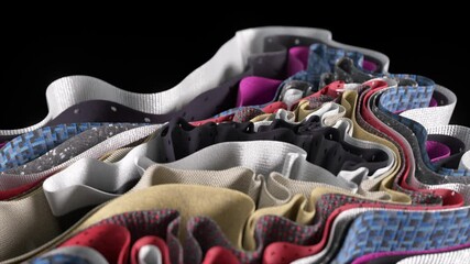 Multiple layers of colorful fabric with varying textures and perforations create a visually appealing wavy pattern, suggesting breathability and flexibility