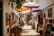 © BerkahStock - Colorful umbrellas shade a narrow, sun-drenched cobblestone street lined with art galleries and shops.