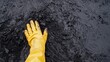 © zakiroff - Gloved Hand Touches Contaminated Earth Depicting Oil Spill, Environmental Cleanup Efforts, Pollution Crisis, Protection Concept