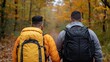 © Sam - Two men, one wearing a yellow jacket and another in a gray hoodie, walking in a colorful autumn forest.