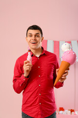 Wall Mural - Young man with soda and ice cream figure  on pink background. Valentine's Day celebration