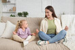 © Pixel-Shot - Nanny with cute little girl meditating on sofa at home