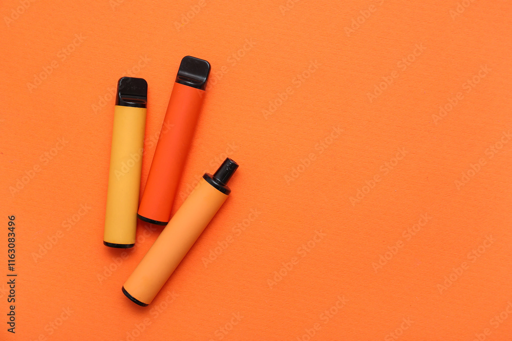 Set of disposable electronic cigarettes on orange background