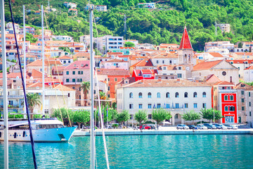 Wall Mural - Colorful buildings with vibrant facades line the waterfront of a charming coastal Makarska town in Croatia. Adriatic Sea filled with docked boats, enhances the picturesque and scenic view