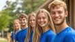 © BrightWhite - Five smiling young volunteers stand in a line outdoors, wearing matching blue shirts, showcasing teamwork and community spirit, eager to make a positive impact.