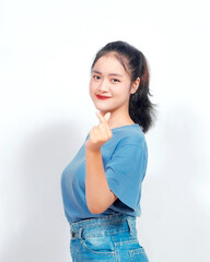 Attractive young Asian woman feels happy and romantic shapes heart gesture expresses tender feelings against White background. People affection and care concept