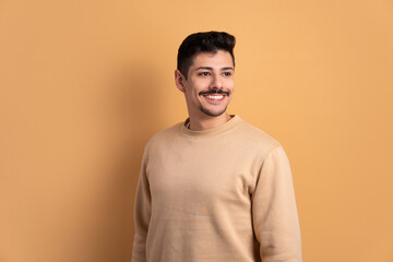 Wall Mural - joyful caucasian man thinking and looking to the side in beige background. portrait, real people concept.