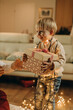 © Westend61 - Happy boy with string light receiving gift from father at home