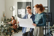 © Westend61 - Smiling colleagues with blueprint standing office