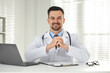© New Africa - Smiling doctor working at table in clinic