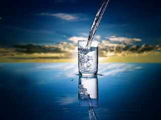 Aufkleber - Water pours into a glass, reflecting on a calm, blue surface beneath a dramatic sunset sky.  The scene evokes purity and refreshment.