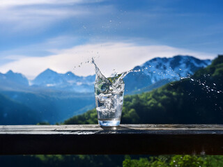 Aufkleber - Refreshing glass of ice water with a splash, set against a stunning mountain backdrop.  The scene evokes purity and serenity.