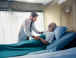 © YiuCheung - A doctor shows compassion while attending to an elderly patient resting in a hospital bed.  The scene emphasizes care and empathy in healthcare.