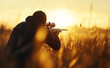 © Curioso.Photography - Silhouette of a sniper aiming in a field during a golden sunset.