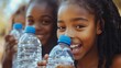 © Ilja - Three Young Girls, Sharing a Moment of Joy and Refreshment, Drinking Bottled Water on a Sunny Day