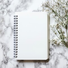 Wall Mural - a spiral bound notebook sits on a marble countertop. the notebook is empty and the countertop is whi
