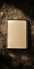 Wall Mural - a notebook with a spiral binding sits on a rock. the notebook is empty. the rock is brown and has a 