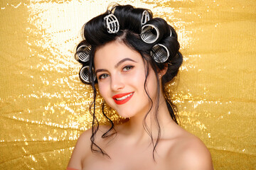 Beautiful girl in hair curlers isolated on gold