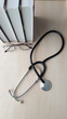 © Lusy Basil - a stethoscope with a pile of books and glasses on a light table by the window