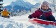 © David Giraud - Des enfants heureux dévalant une pente en luge dans un paysage enneigé, riant et s'amusant ensemble par une journée d'hiver ensoleillée.