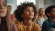 © GrayFrog - Group of children listening in a classroom with a young boy in a yellow sweater with curious expression.