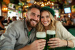 © Jean van der Meulen - A lively pub scene with a happy couple, smiling at the camera while enjoying their green St. Patrick's Day beers.