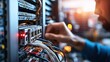 © RUENGWILAI - A technician is working on a server rack, connecting cables and ensuring network functionality in a data center environment.