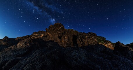 Wall Mural - beautiful night sky with stars and the milky way over a rocky mountain, the silhouette of a person s