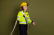 © deagreez - Confident mature female firefighter in high-visibility gear and helmet on khaki background, symbolizing courage
